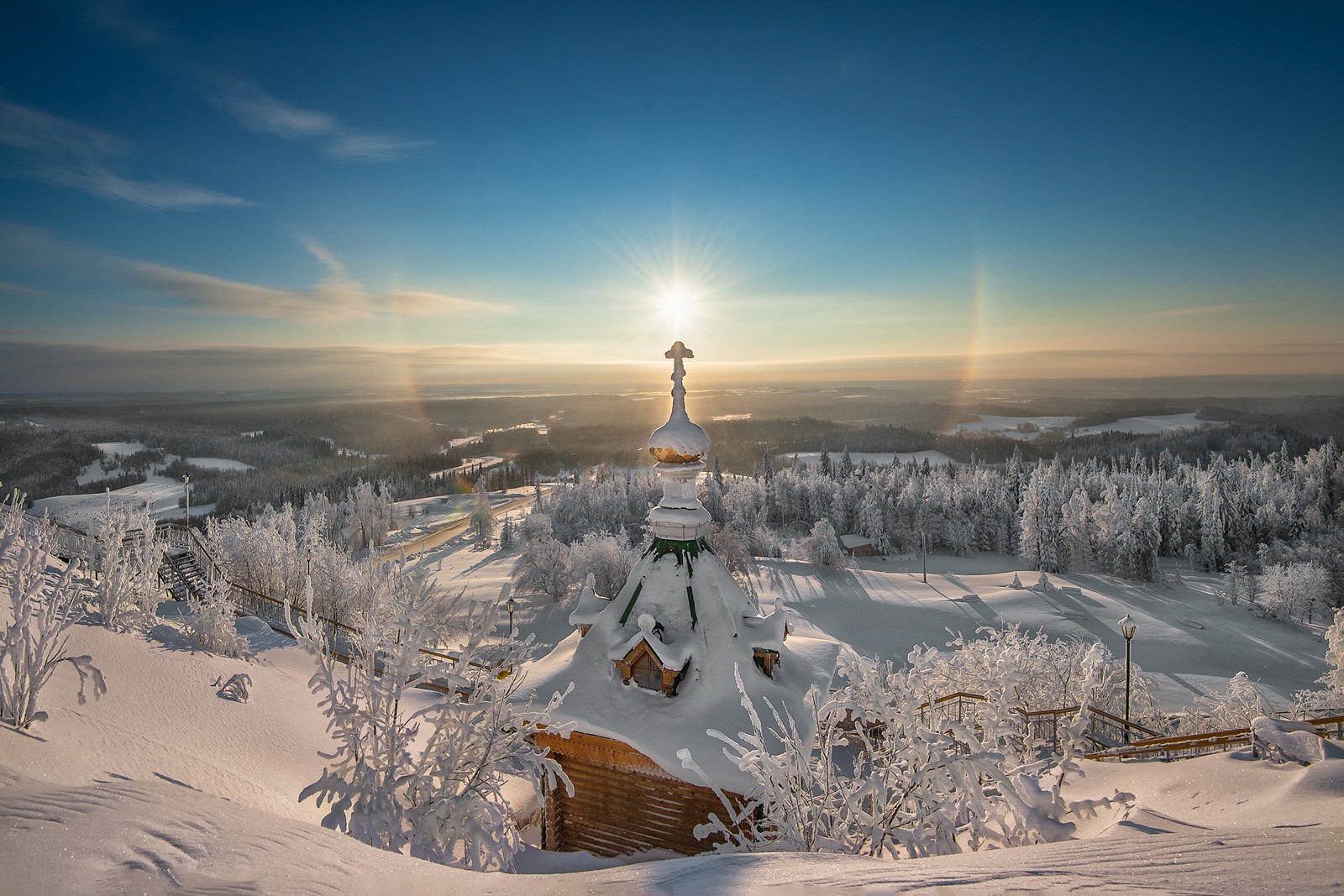 Vue d'une église dans la neige avec le soleil brillant au-dessus des arbres (hiver, neige, gel, arbre, montagne)