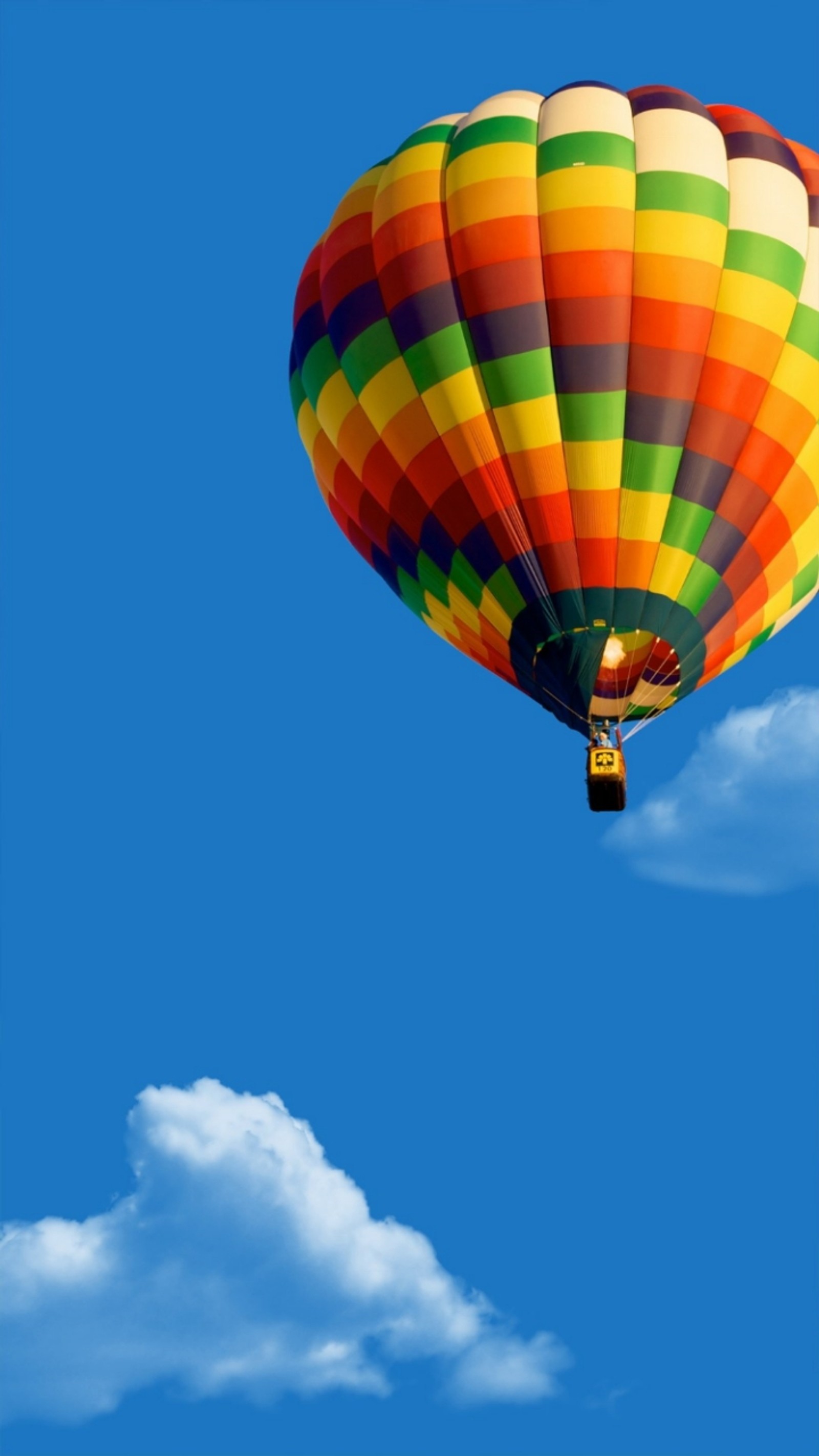 Un globo aerostático de colores volando en el cielo azul (globo, azul, nubes, cielo)