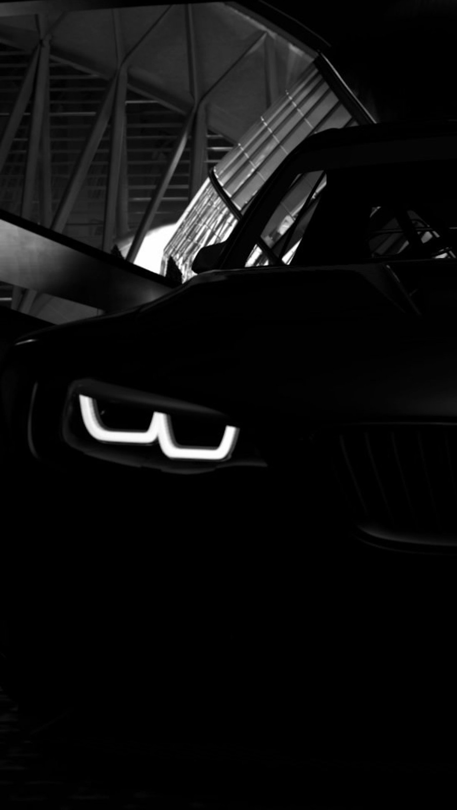 Una foto en blanco y negro de un coche en una habitación oscura (negro, bmw, coche)