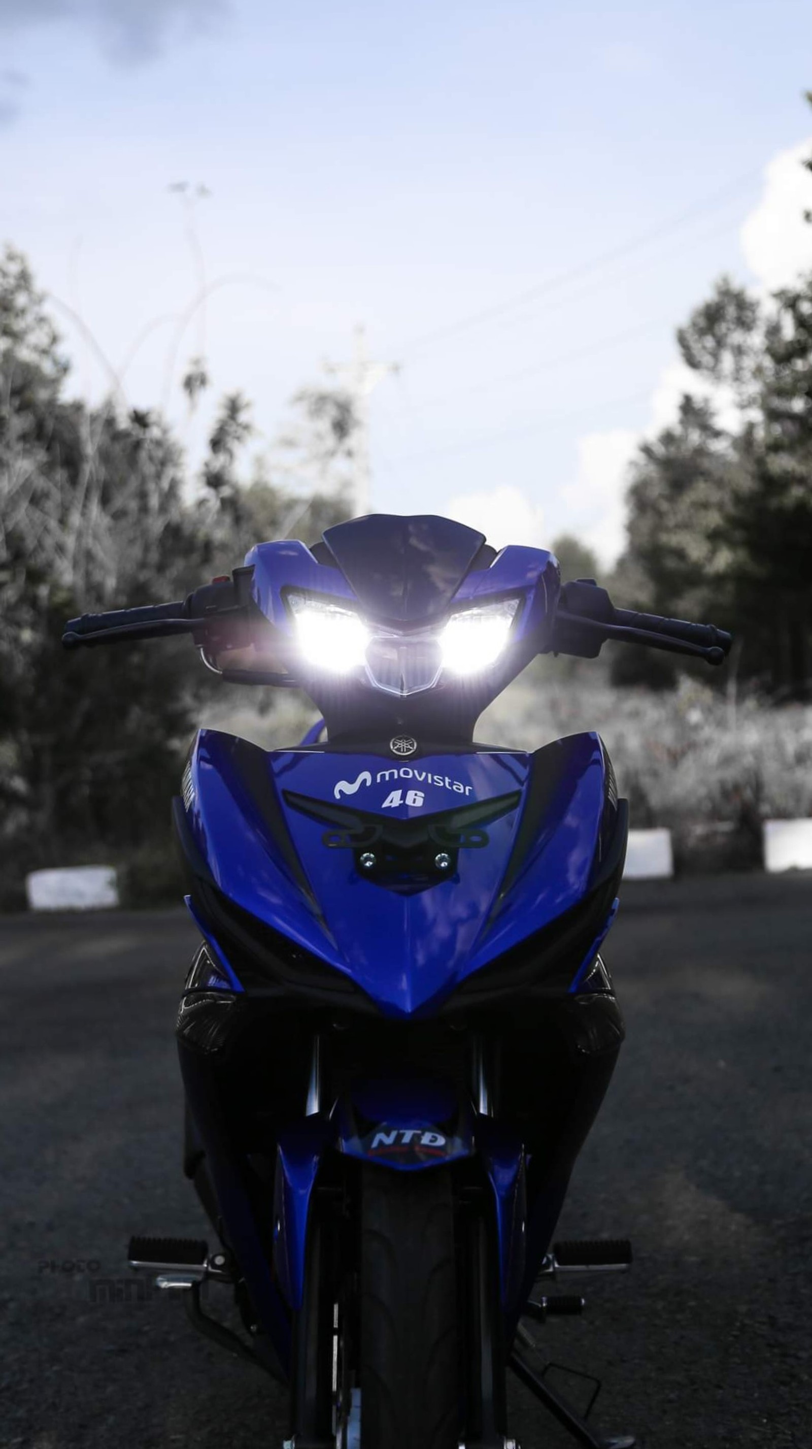 Hay una motocicleta azul estacionada en la calle con las luces encendidas (mopedyamahay15zr, y15zr, yamaha exciter 150, yamahaexciter150, yamahateam)