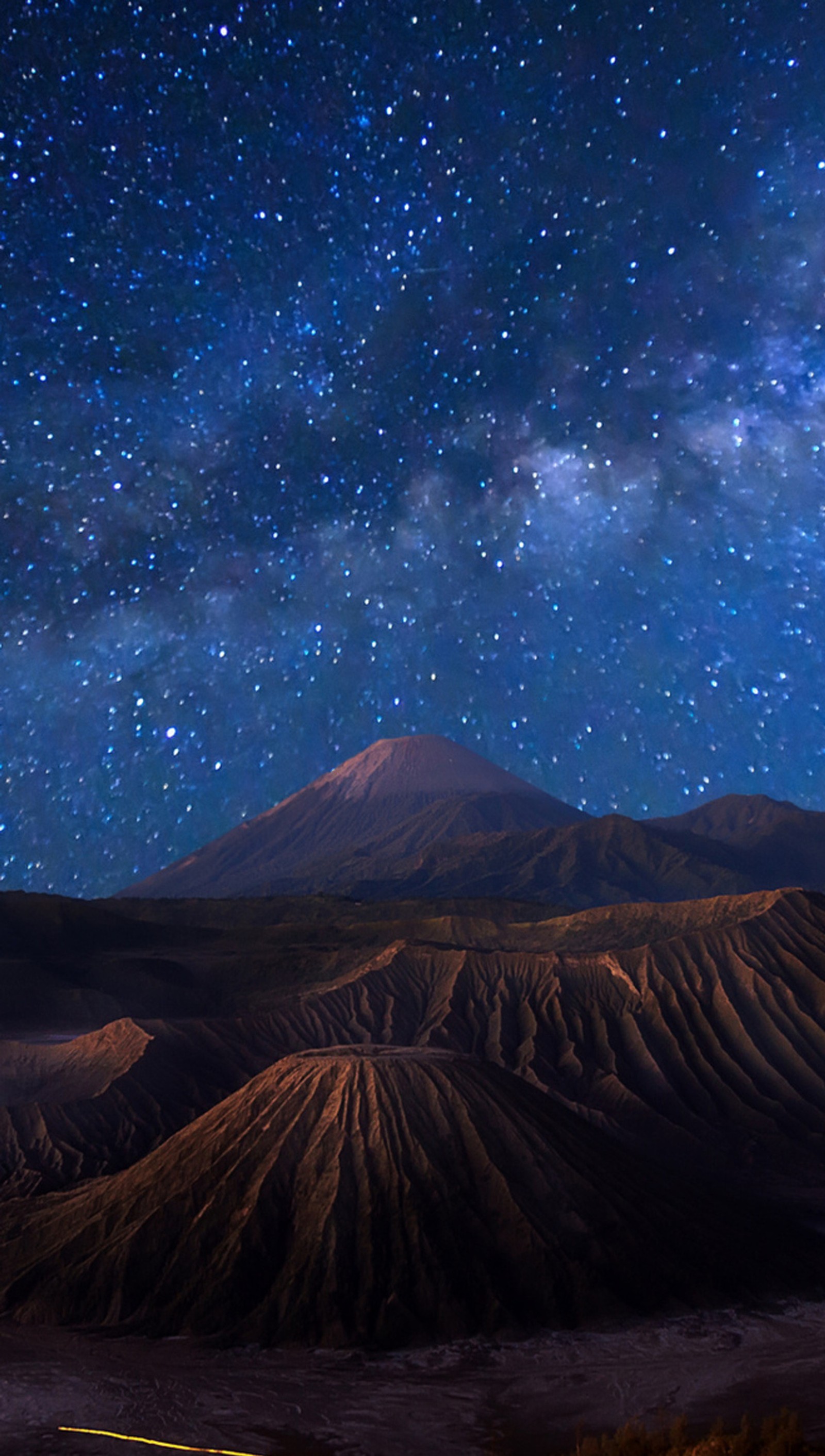 Cielo nocturno estrellado sobre una cordillera con una carretera pasando (fgh)