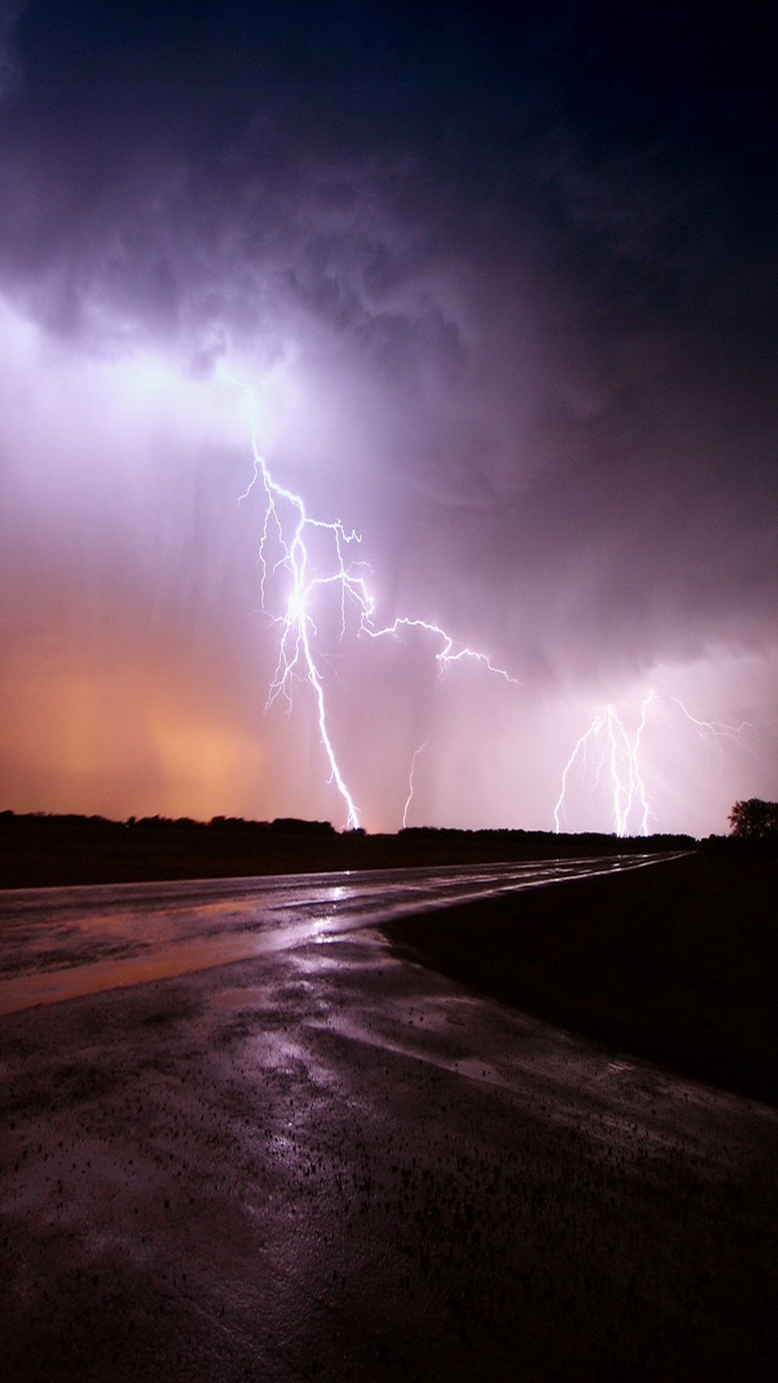 Lightning flashes over a beach and a body of water (lightning, rain)