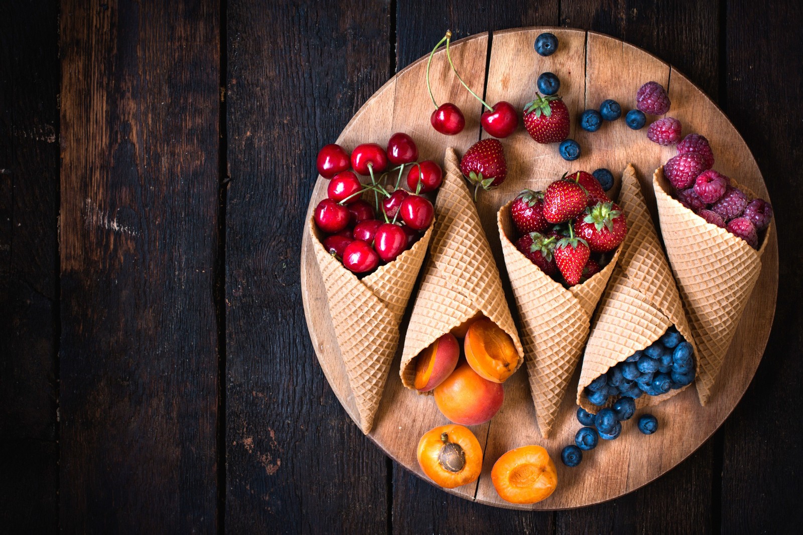 A close up of a plate of fruit with cones on it (kitchen, vegetable, eating, wood, fruit)