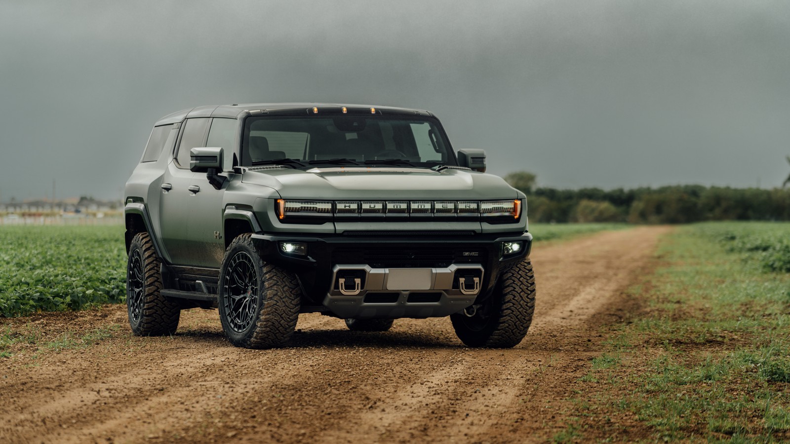 Un camión gris conduciendo por un camino de tierra junto a un campo (gmc hummer ev, al aire libre, 5k, 8k, camino de tierra)