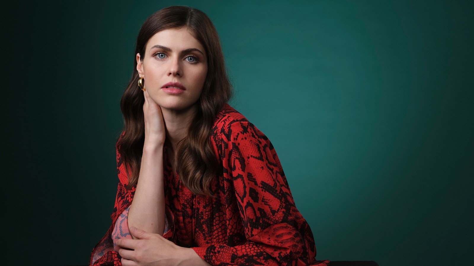 Une femme en robe rouge et noire assise sur une chaise (alexandra daddario, actrice, célébrité, femmes, filles)