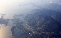 Vista aérea de uma paisagem montanhosa de estação de montanha, apresentando uma mistura serena de cristas, vales e nuvens sob um vasto céu.