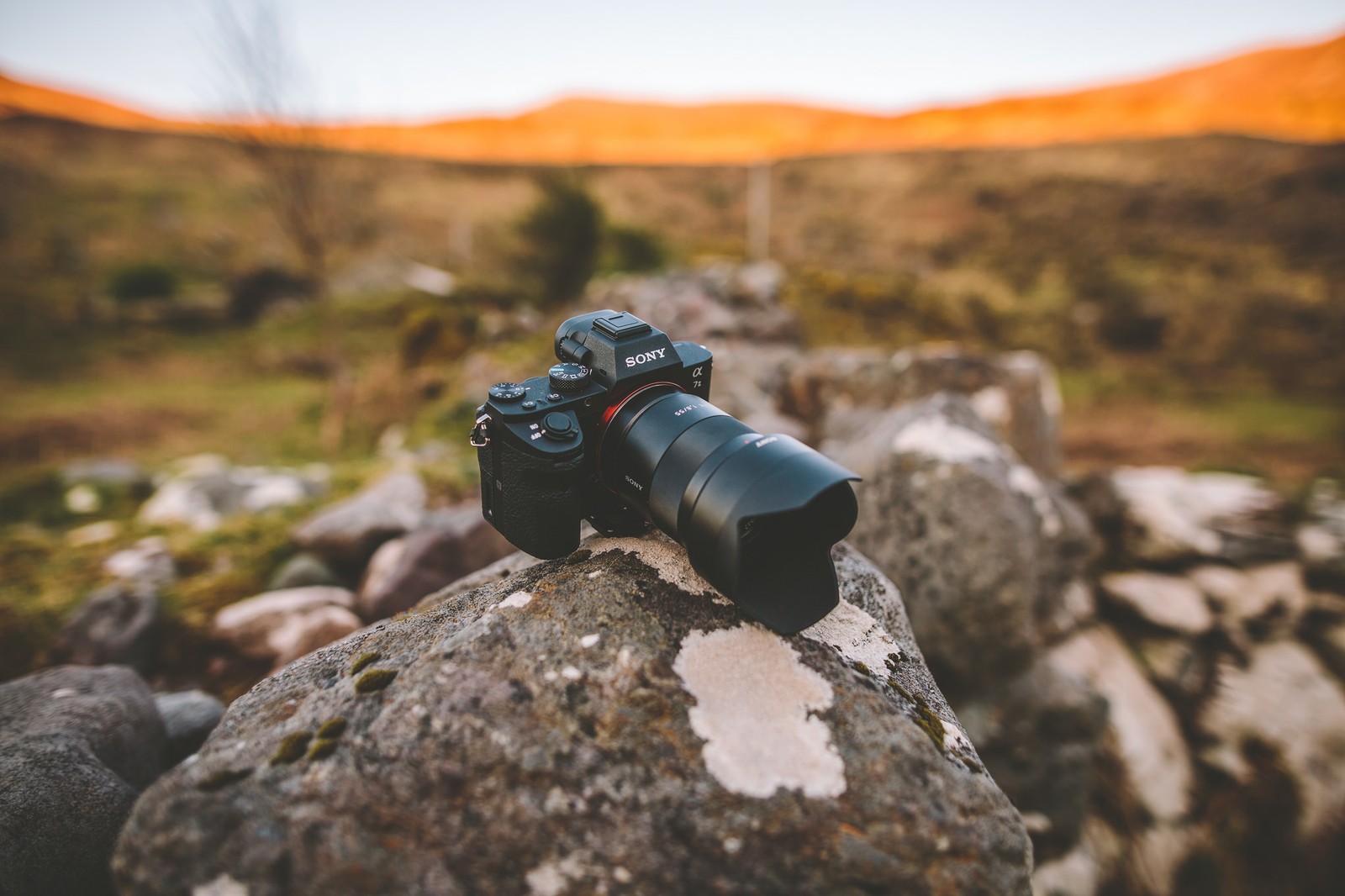 Close-up de uma câmera em uma pedra em um campo (câmera, rocha, lente de câmera, canhão, arma)