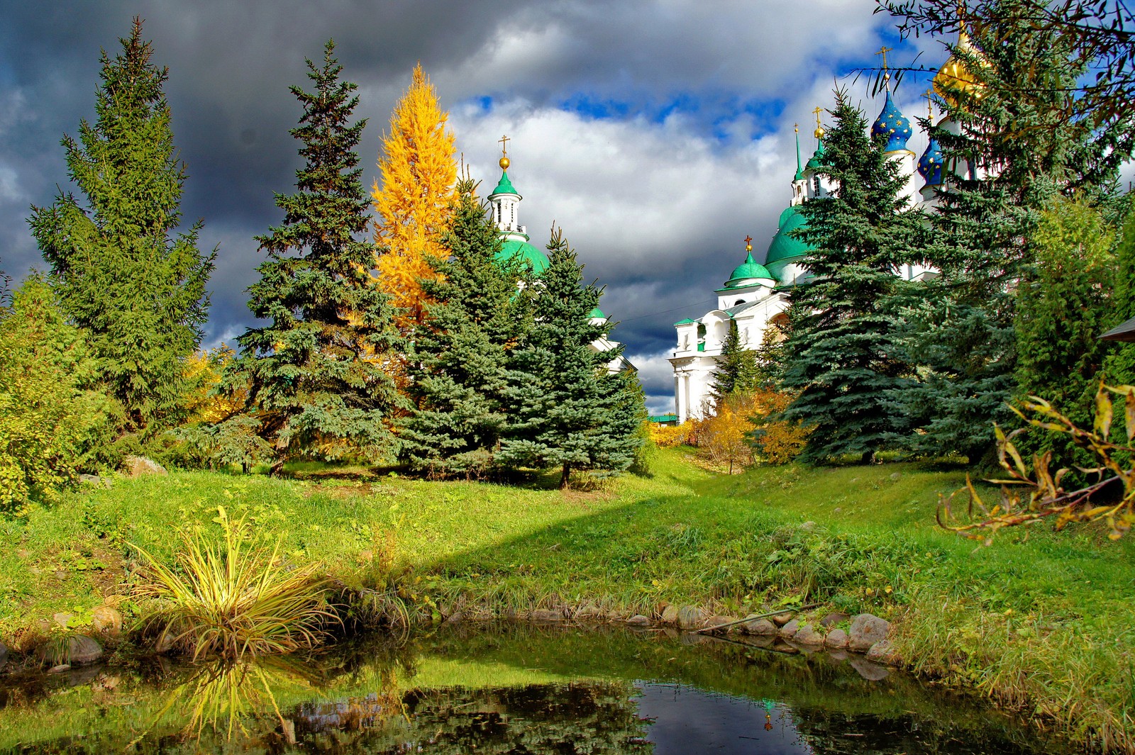 Une vue d'un petit étang devant une église (nature, épicéa, arbre, végétation, biome)