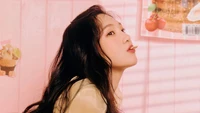 Park Soo Young von Red Velvet strahlt Freude in einer pastellfarbenen Umgebung aus und genießt einen verspielten Moment mit einem Snack.