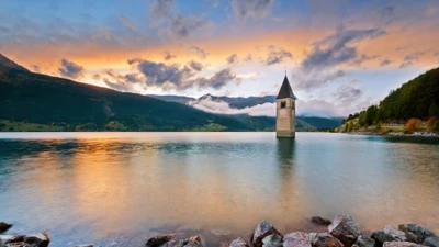 Sérénité du coucher de soleil : La tour de cloche submergée du lac Resia, Italie