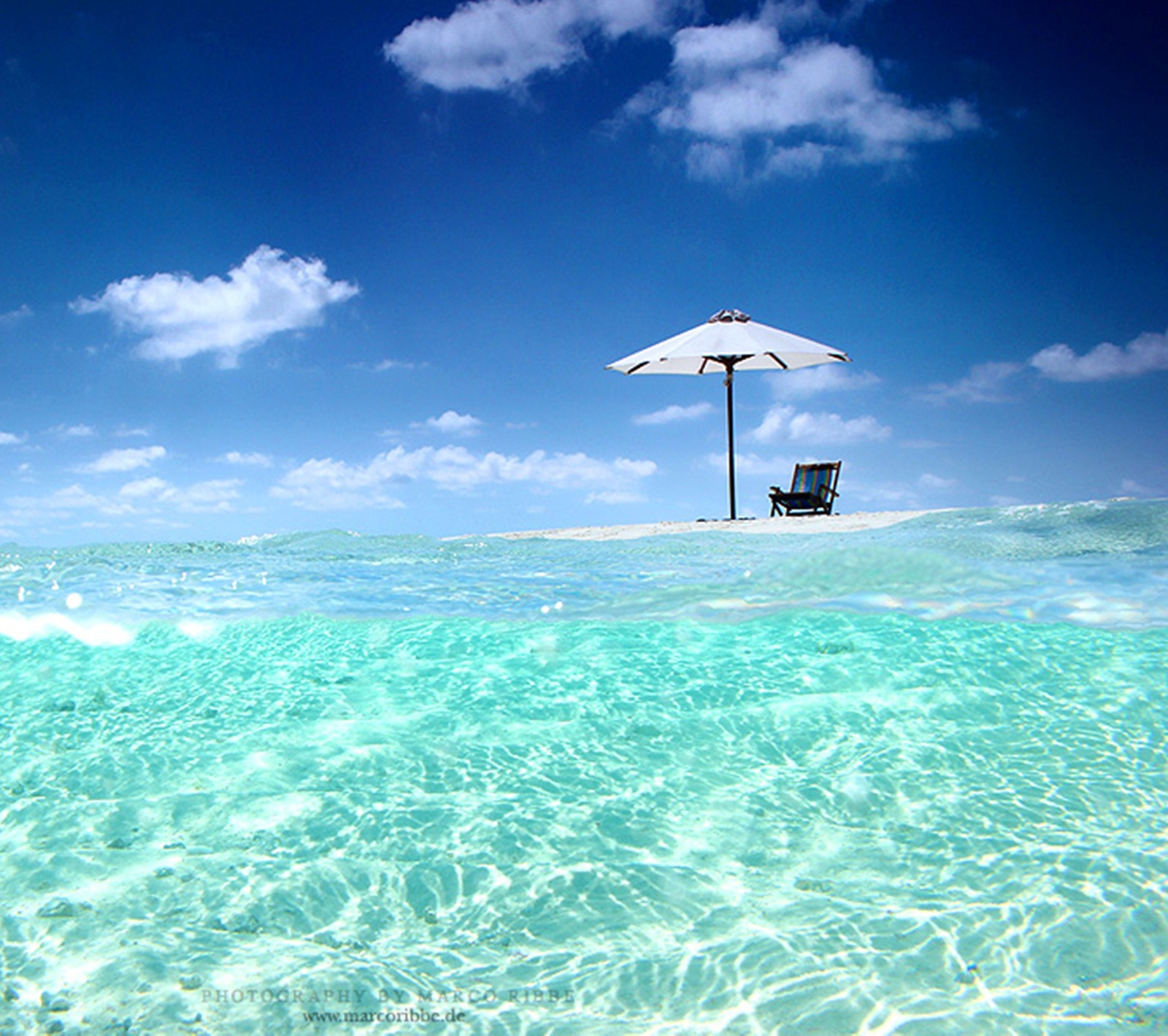 Ein stuhl und ein sonnenschirm im wasser mit blauem himmel (strand, natur, meer, sommer)