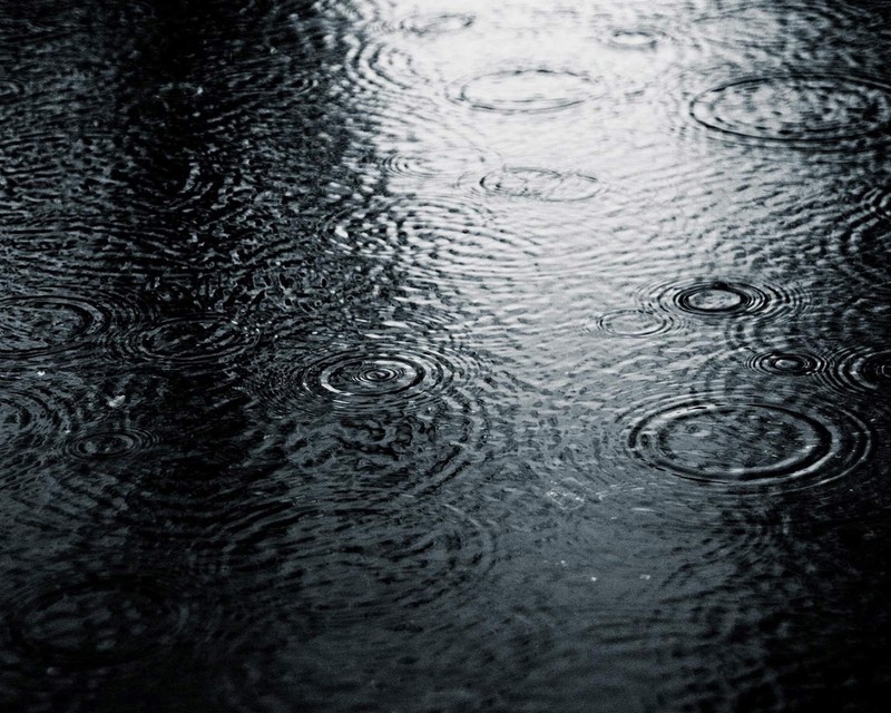 Um close-up de gotas de chuva em uma superfície molhada com fundo preto (gotas, rua)