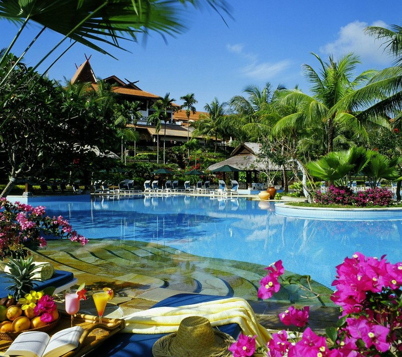 Há uma piscina com muitas flores e uma mesa com um livro (aqua, legal, bebidas, hq, lazer)