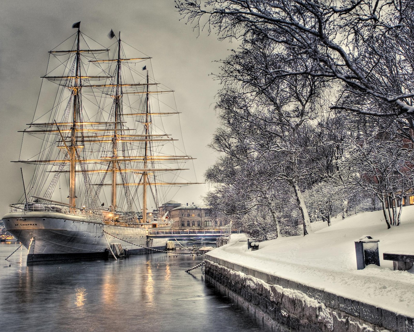 Vela ancorada em um porto nevado com uma paisagem nevosa (cais, veleiro, navio, neve, inverno)