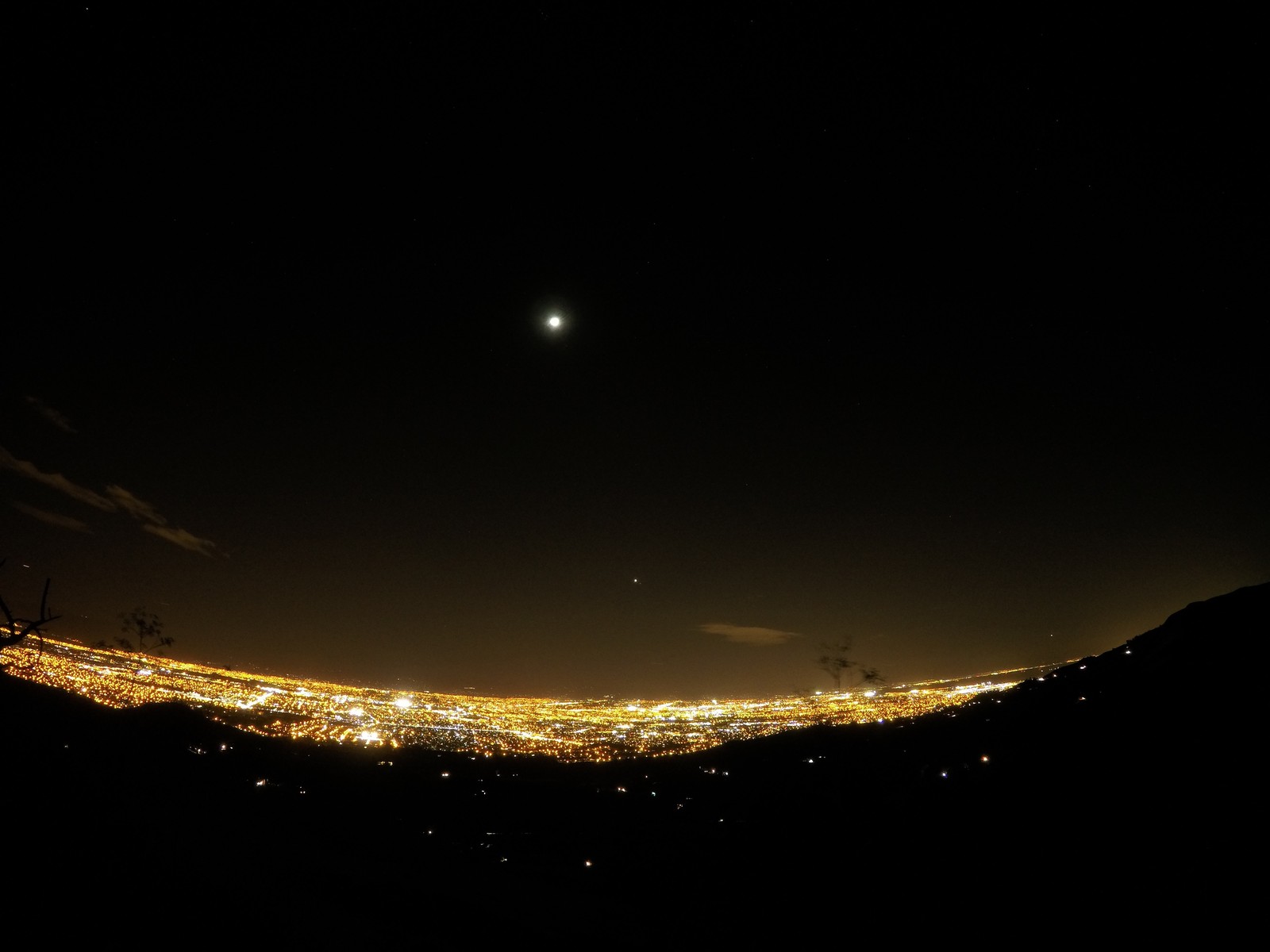 Vue nocturne d'une ville avec une lune et quelques nuages (nuit, objeto astronomique, lumière, événement céleste, atmosphère)