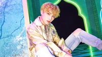 Xiaojun de NCT U posant dans une tenue stylée, mettant en valeur un arrière-plan vibrant avec des lumières néon colorées.