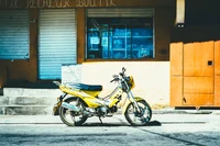 Scooter amarillo aparcado en una calle iluminada por el sol cerca de un edificio vibrante, mostrando el transporte urbano y el estilo automotriz.