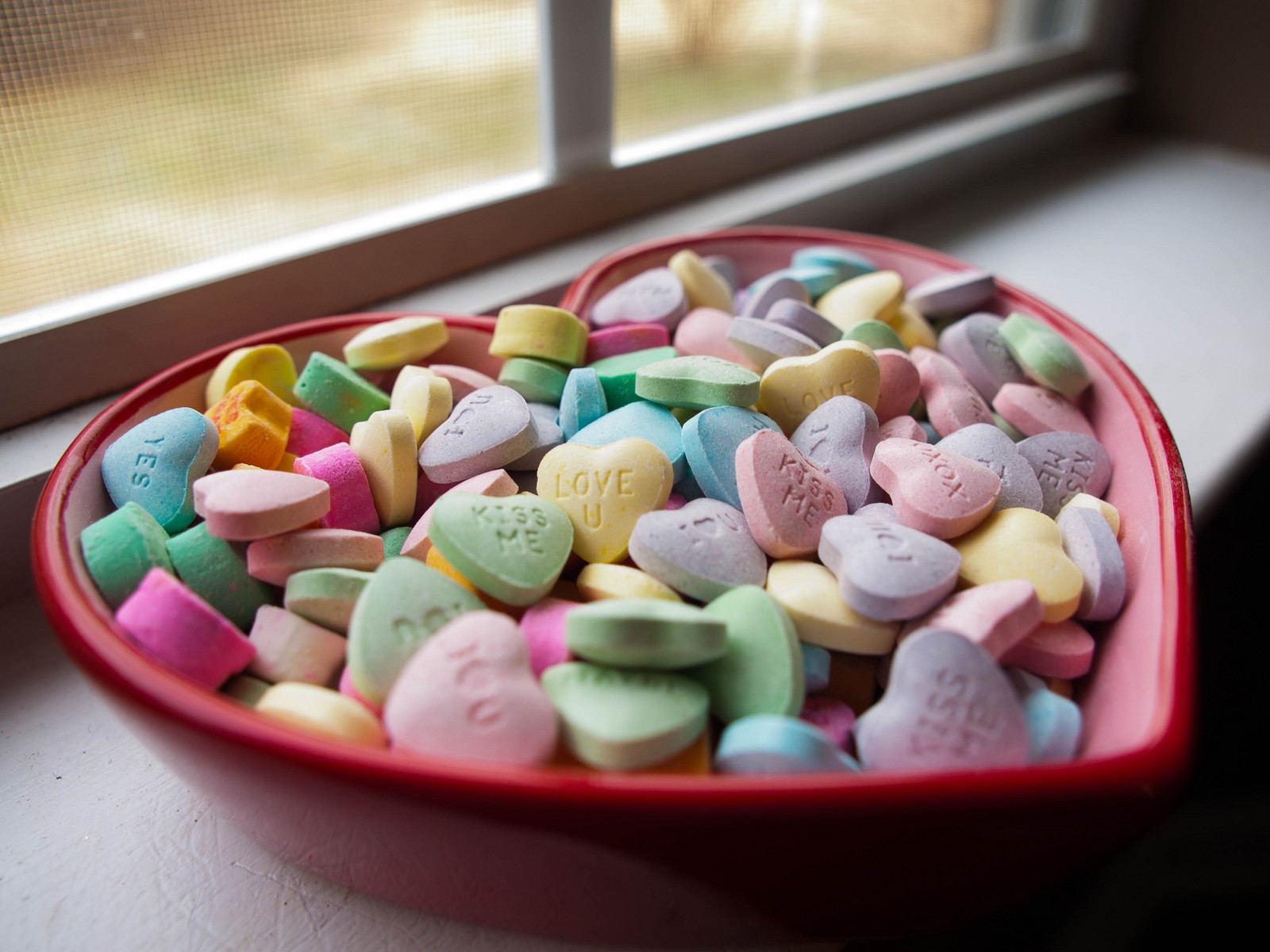 Image déformée d'un bonbon en forme de cœur dans un bol rouge (saint valentin, cœur, douceur, nourriture, cuisine)