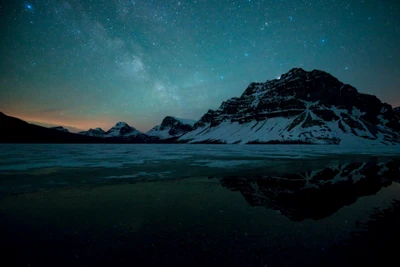 Nuit étoilée arctique sur un lac gelé et des montagnes majestueuses