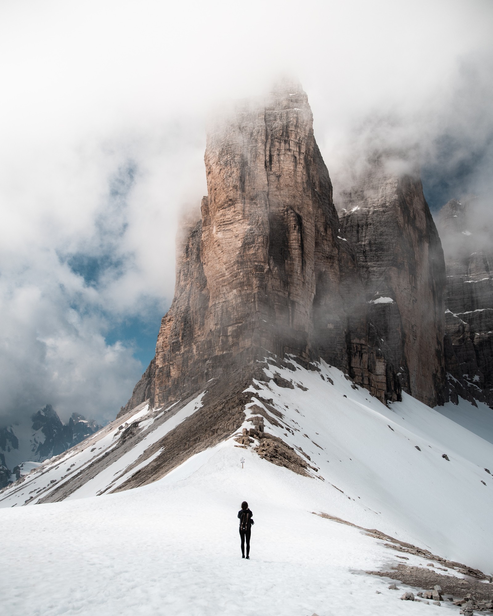 Un homme se tenant sur une montagne enneigée avec une montagne en arrière-plan (montagne, formes montagneuses, neige, forme glaciaire, hiver)