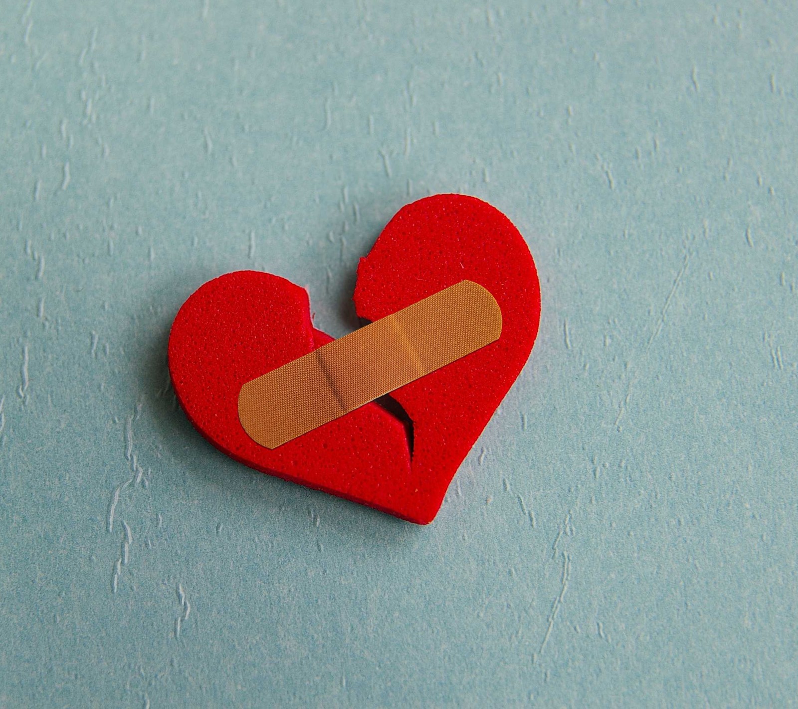 Arafed heart with a band - aid on it on a blue surface (broken heart p, r broken heart)