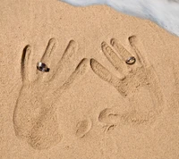 Symbol der Liebe: Eheringe und Handabdrücke im Sand