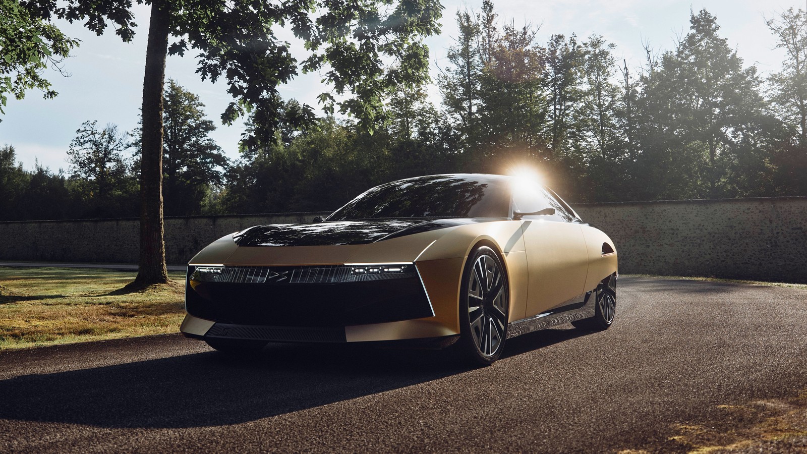 A gold car driving down a road next to a forest (ds sm tribute, concept cars, 5k, 2024, cars)