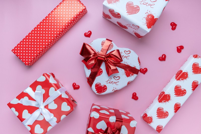 Подарки на день святого валентина расположены на розовой поверхности (valentine gifts, сердцевидная форма, подарочные коробки, красные сердца, представляет)