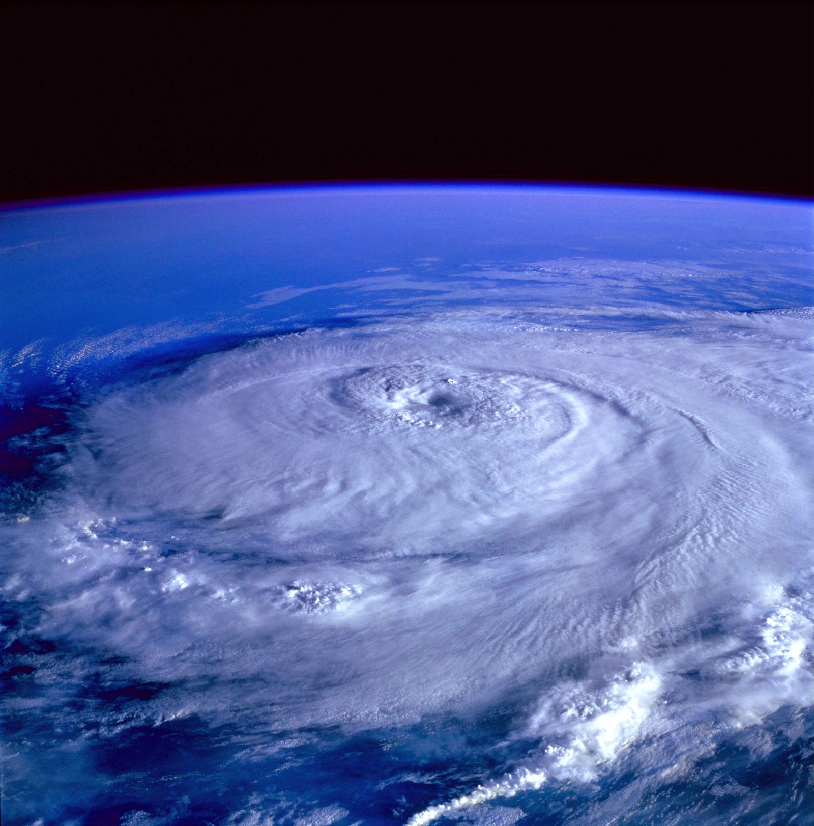 Arafed view of a hurricane from space with a satellite in the background (tropical cyclone, storm, atmosphere, cyclone, outer space)