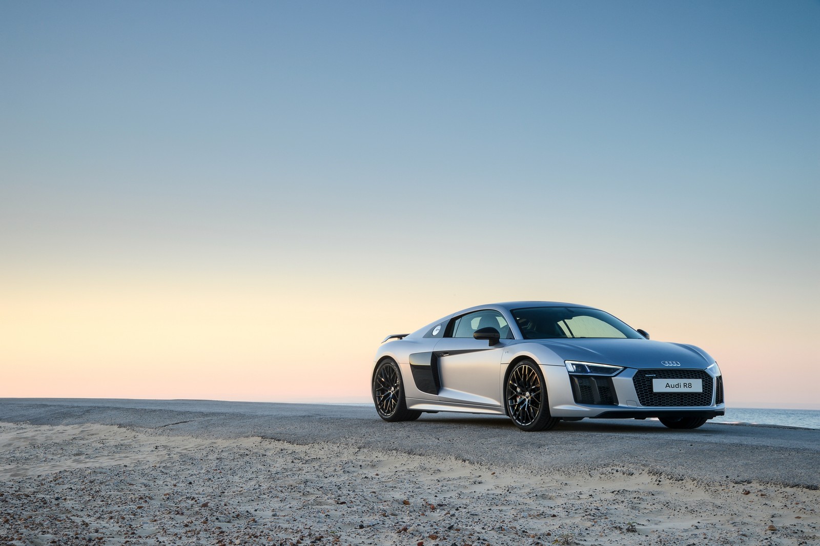 Une voiture de sport audi argentée garée sur une plage près de l'océan (audi r8, audi, voiture, voiture de sport, roue)