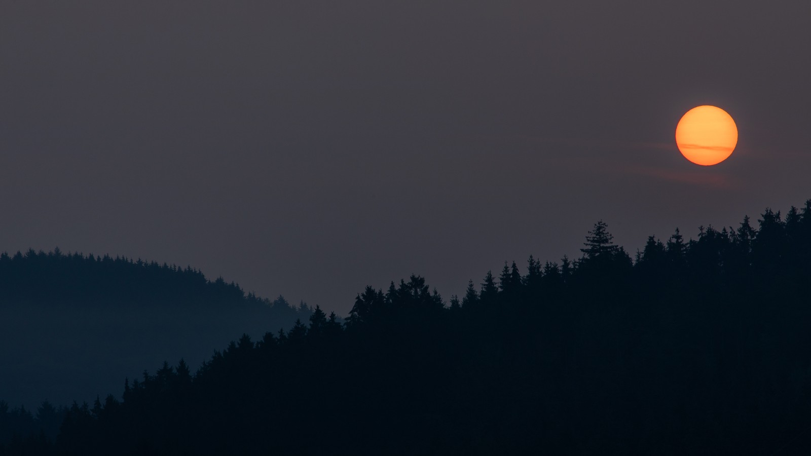 Arafed view of a sun setting over a forested area (mountain, dawn, sky, darkness, celestial event)