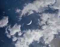 Luna creciente iluminada por estrellas contra un cielo azul nublado