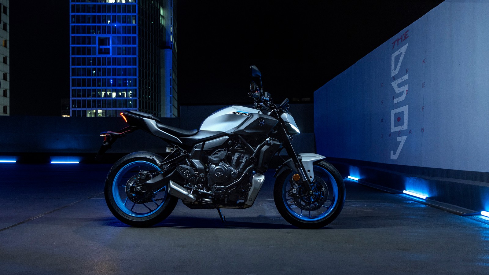 Uma motocicleta estacionada em um estacionamento à noite com luzes da cidade (2025, yamaha mt 07, noite, bicicletas, papel de parede 4k)