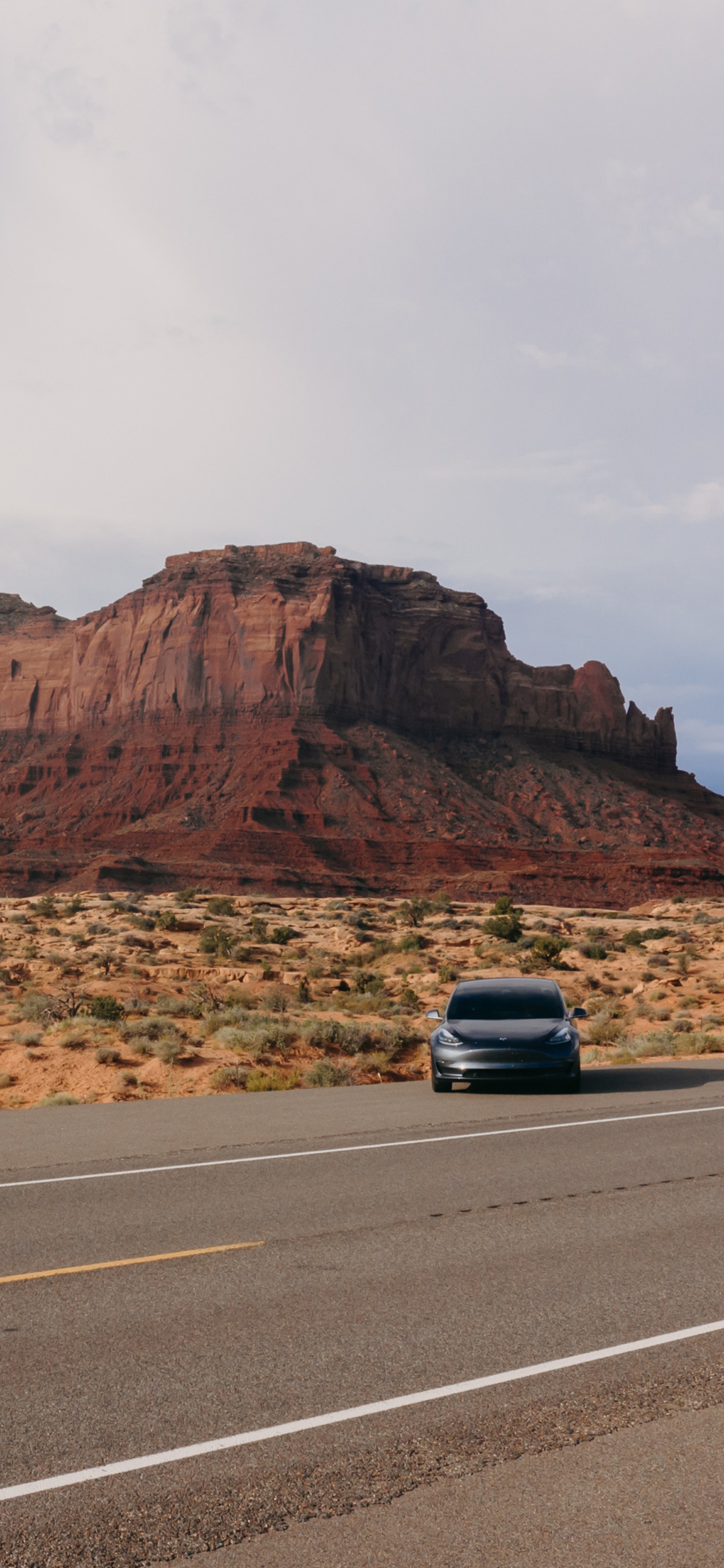 Une voiture roule sur la route dans le désert (tesla model 3, tesla, monument valley, roi, voiture électrique)