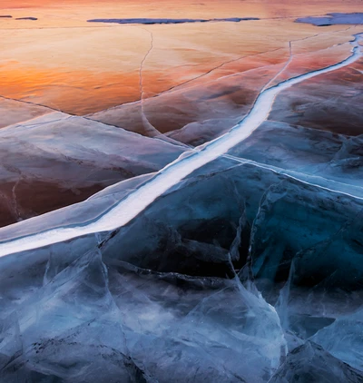 Paisaje helado: grietas y carámbanos en una capa de hielo al atardecer