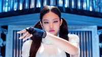 Kim Jennie of Blackpink showcasing powerful stage presence with striking makeup and a captivating pose.