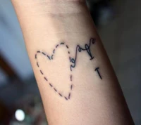 Tatuaje de un corazón cosido entrelazado con un delicado diseño de pluma.