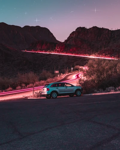 Coche de tamaño mediano en una carretera sinuosa bajo un cielo estrellado