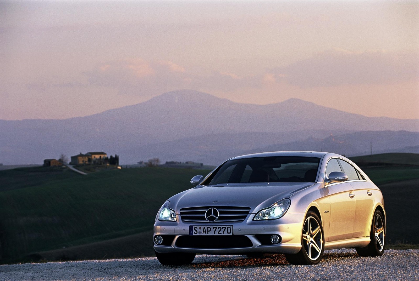 Um carro prateado estacionado em uma estrada de cascalho com montanhas ao fundo (carro, mercedes benz e class, roda, mercedes benz classe clk, mercedes benz clk class)