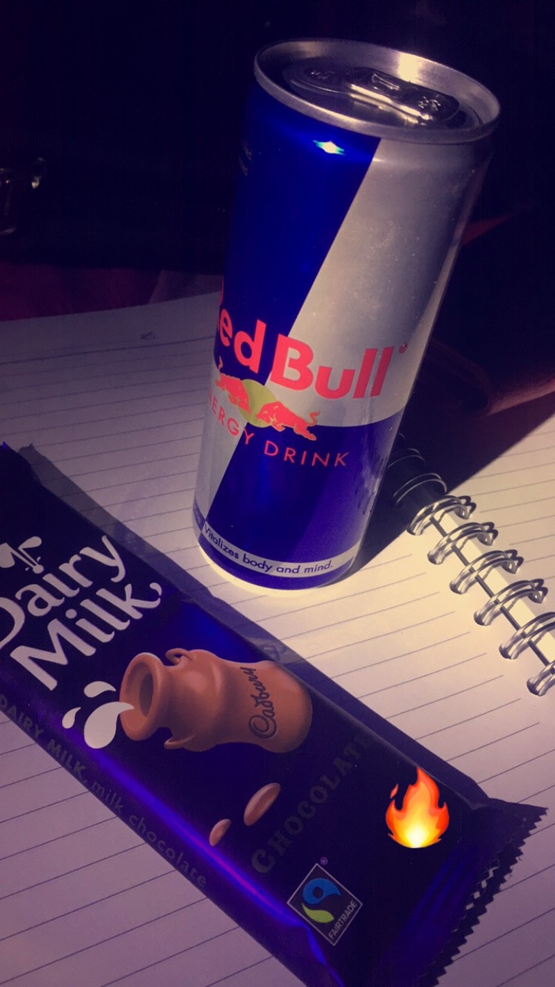 Крупный план банки red bull рядом с шоколадным батончиком (dair milk, ред булл, redbull)