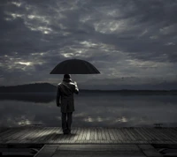 Homem solitário com guarda-chuva em um píer noturno