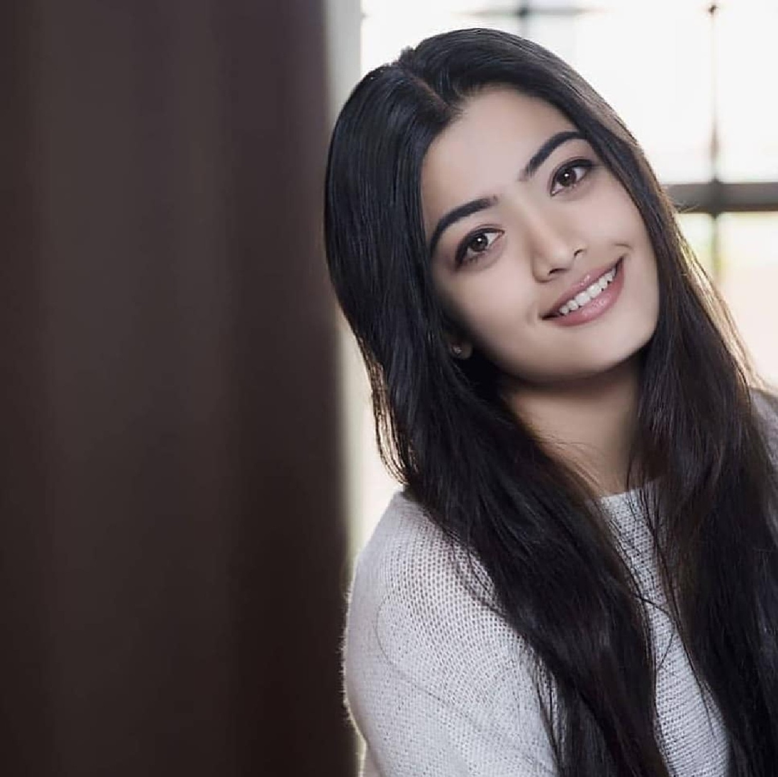 Une femme arabe avec de longs cheveux noirs souriant et regardant la caméra (bollywood, héroïne, rashmika)