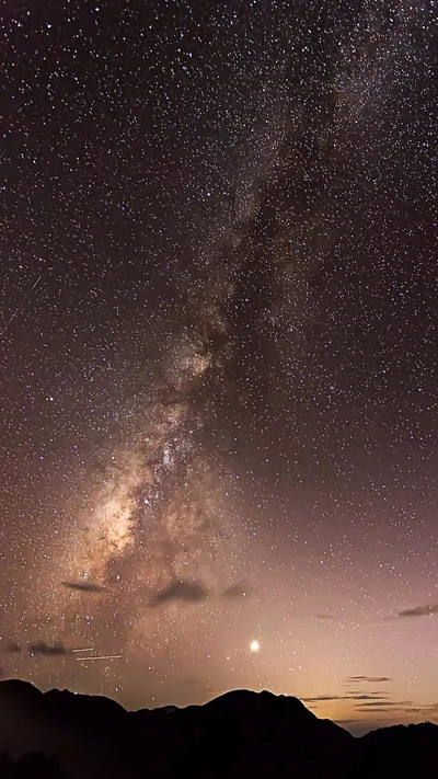 Via Láctea iluminada por estrelas sobre montanhas serenas