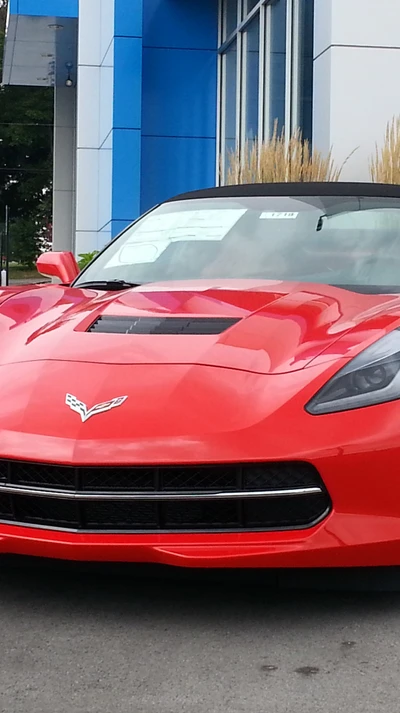 Red Chevrolet Corvette with sleek design and convertible top, showcased in a modern setting.