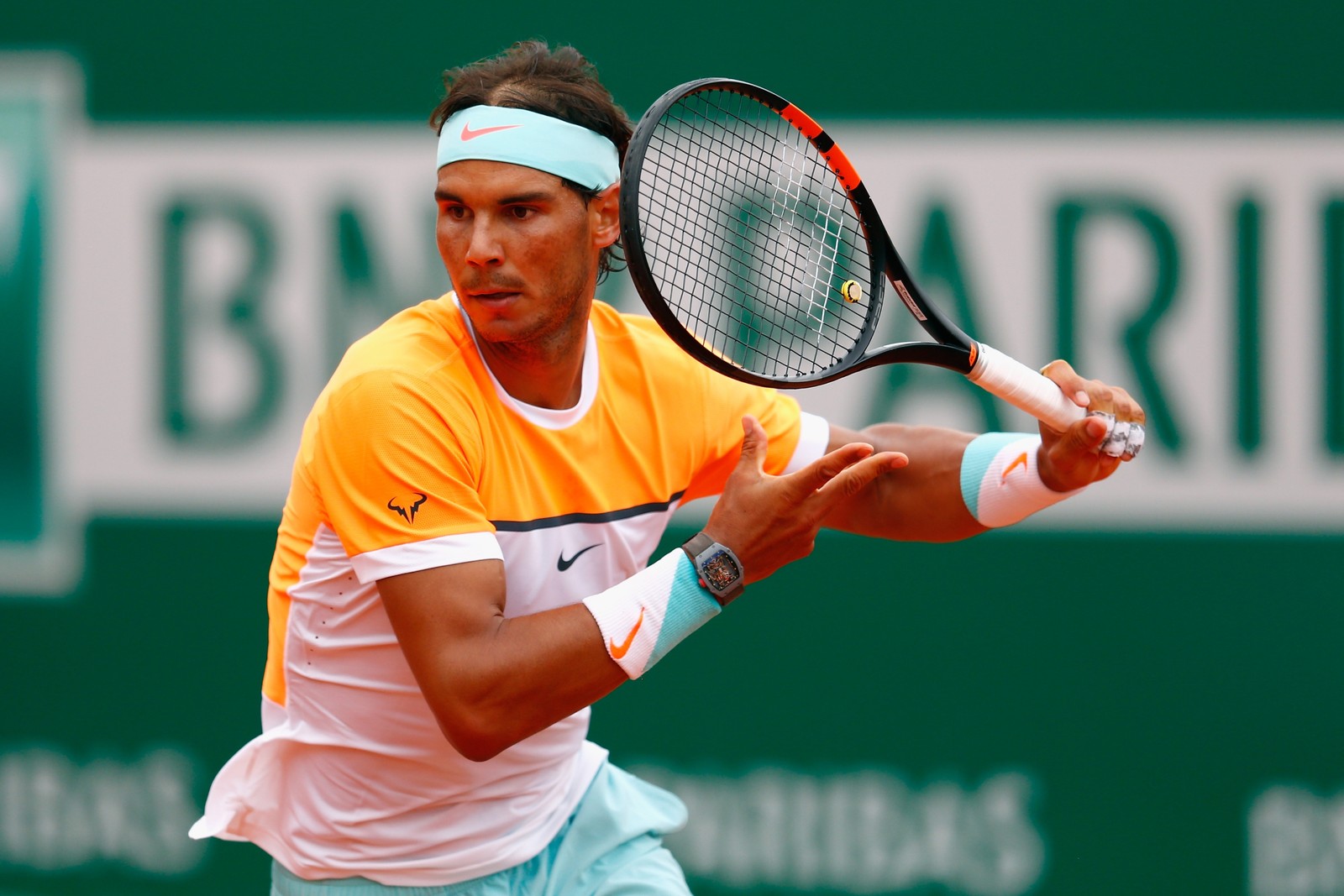 Joueur de tennis en chemise orange et blanche balançant une raquette (tennis, joueur de tennis, sports, raquette, sport de raquette)