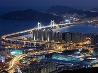 Paisaje urbano nocturno de Busan: horizonte iluminado con puente y diseño urbano