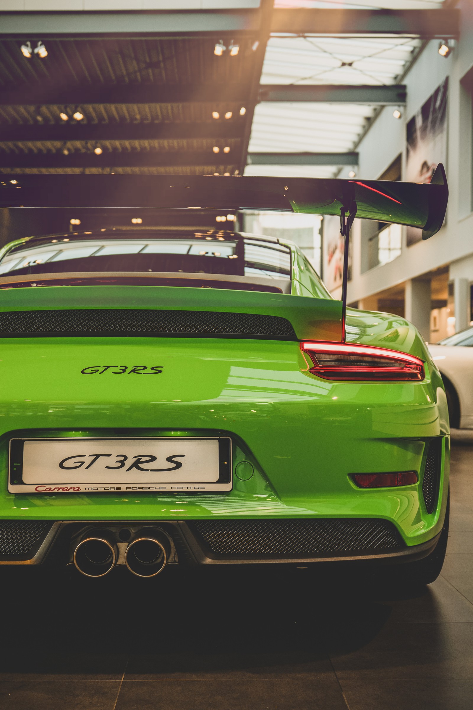 A close up of a green sports car parked in a showroom (porsche 911 gt3, porsche, sports car, car, supercar)