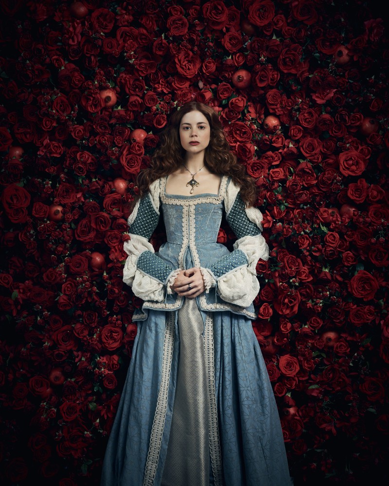 Арабская женщина в синем платье стоит перед стеной из роз (charlotte hope, the spanish princess, сериал, сезон 2, кино)