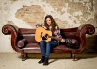 Musician Sitting on a Couch with Acoustic Guitar