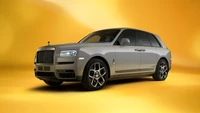 Rolls Royce Cullinan em Cinza Tempestade contra um fundo Laranja Vibrante